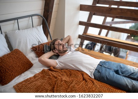 Necessary relaxation. A smiling young man relaxing in his bedroom