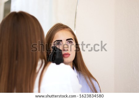 Female cosmetologist performs eyebrow correction on beautiful models in the beauty parlor. Fair-haired girl. Close-up. Facial care. Vitiligo pigmentation model. Safe eyebrow tinting with henna. Salon