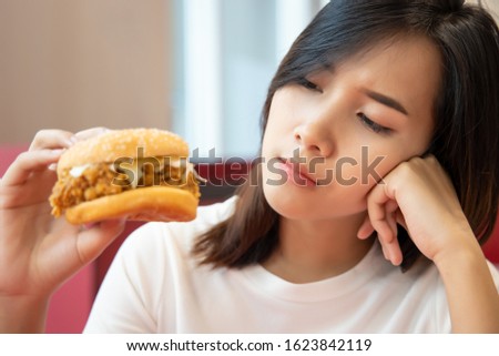 hungry worried woman on diet looking and hesitating to eat fried chicken burger sandwich; concept of unhealthy delicious food, unhealthy eating habit, junk food, fast food, woman having no appetite Royalty-Free Stock Photo #1623842119