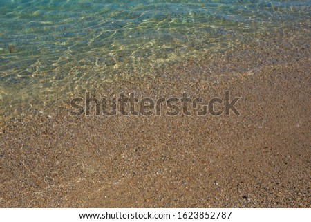Beautiful clean transparent water of Aegean sea splashing softly at scenic sandy beach outdoor. Greece landscape. Horizontal color photography.