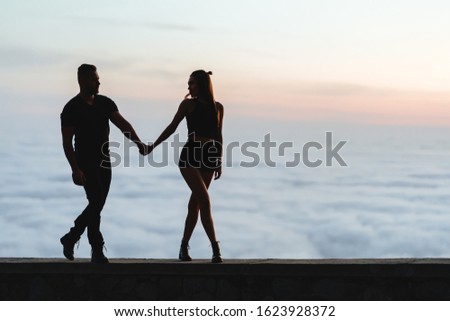 Happy couple embracing and watching one another under the sunset sky