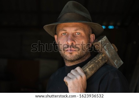 Man in a worker hat with a hammer and glanders