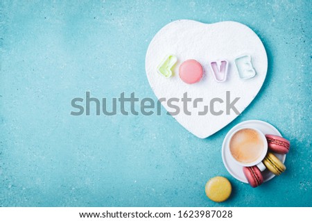Creative layout made with Love letters on white plate, cup of coffee and macarons. Greeting card. Colorful turquoise background.