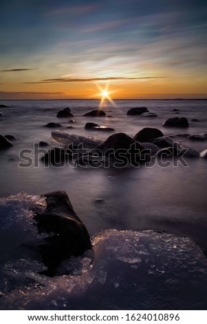 Beautiful sunrise with icy and rocky foreground in Baltic Sea north Sweden. A long exposure.