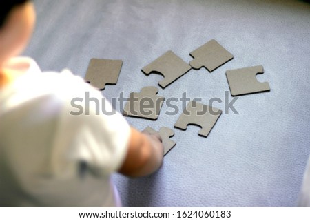 Backward shot of adorable little boy at home playing with puzzles.Happy childhood concept with young boy placing puzzle pieces.Hands of preschool kid make picture connect puzzle piece.Learning concept