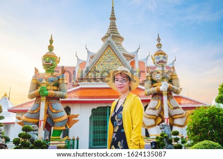 Outdoor portrait of a smiling Asian girl at Wat Arun Bangkok, Thailand. Tourist on holiday vacation trips. Travel holiday relaxation. Beauty and lifestyle concept. Selective soft focus.