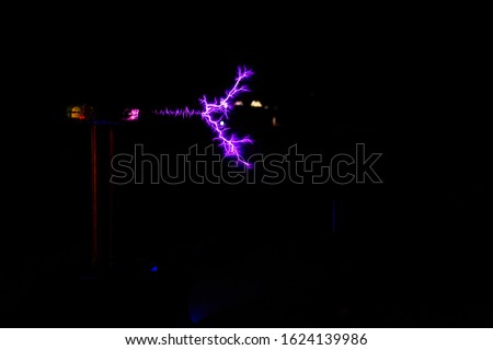 Tesla coil in operation with lightning strikes