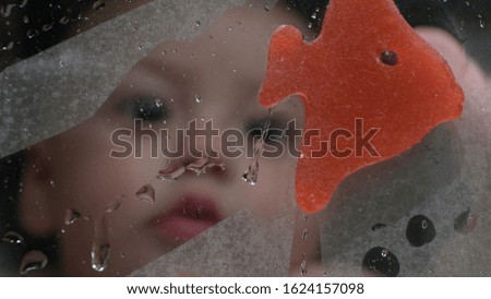 
Baby seen through shower window. Toddler looking at steam vapor droplets