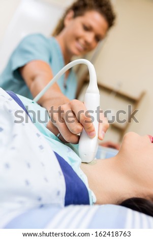 Young patient undergoing ultrasound of thyroid gland in hospital room
