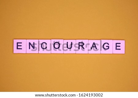 Encourage word wooden cubes on yellow background.