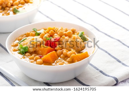 Curry with chickpeas, pumpkin, zucchini and cauliflower in white bowls on the table. Vegetarian curry with stewed vegetables. Traditional indian cuisine, vegan food. Royalty-Free Stock Photo #1624195705