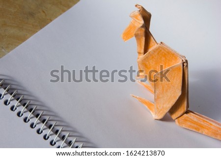 orange kangaroo origami on white notebook 