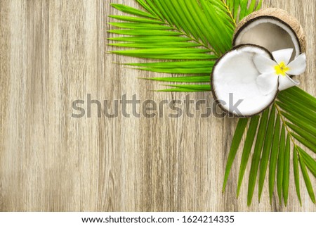 Still life of coconut, palm leaves, plumeria flower on a wooden background. Copy space Composition Tropical walnut top view.