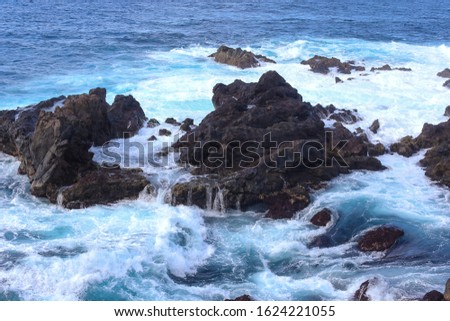 Ocean waves crashing onto the rocks in the sunset. Blue azure water