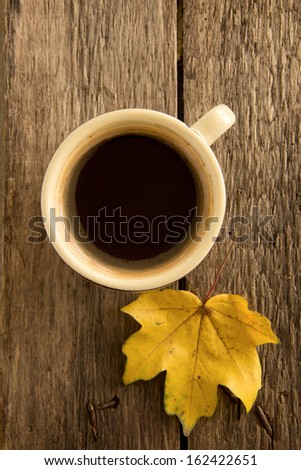 A cup of coffee on a background of maple leaves.