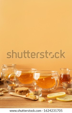 Two cups of tea with lemon, honey, ginger root ingredients and ginger biscuits on wooden table. Natural medicine concept. Mockup for your design. Close-up.