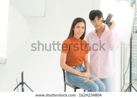 Young Asian beautiful woman model in a studio young Asian man photographer is shooting with a digital camera in studio at home