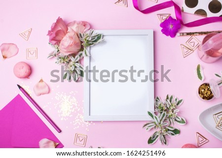 Empty white frame, pink flowers and pink feminine objects on a pink background. Spring concept. Working place