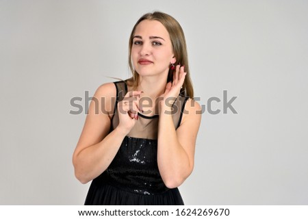 Universal concept horizontal portrait of a woman on a white background. A photo of a pretty smiling girl with long hair and excellent make-up in a black dress stands in different poses.