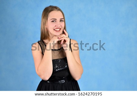 Universal concept horizontal portrait of a woman on a blue background. A photo of a pretty smiling girl with long hair and excellent make-up in a black dress.