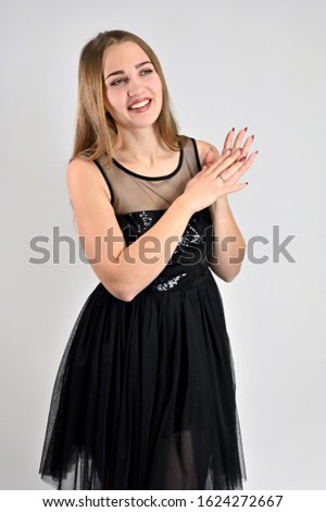 Universal concept vertical woman portrait on a white background. A photo of a pretty smiling girl with long hair and excellent make-up in a black dress is standing in various poses in the studio.