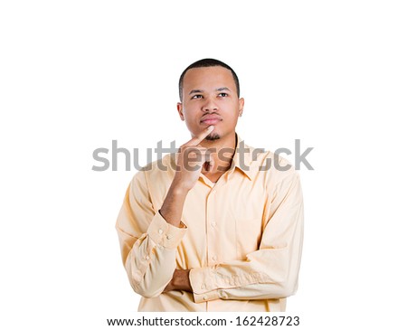 Closeup portrait of young man thinking daydreaming deeply about something with hand on chin looking upwards, isolated on background with copy space to left. Human facial expressions signs and symbols