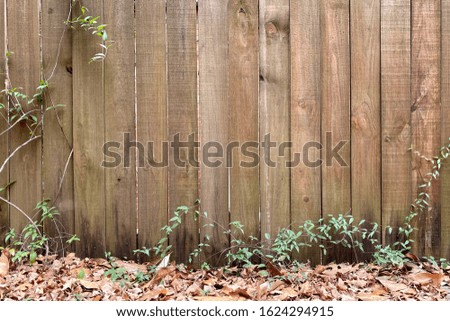 an old wooden fence with fall leaves on the ground