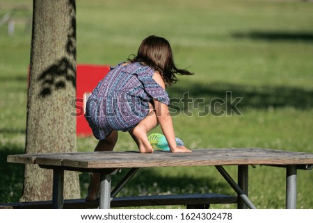 unknown little girl is playing on a picnic table