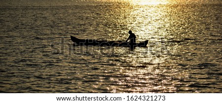 Lone fisherman at the dusk and sunset sails through the coast