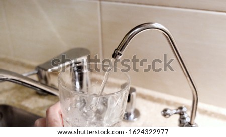 Water being poured into glass from kitchen tap. Concept. Close-up of tap water being poured into a glass in the kitchen
