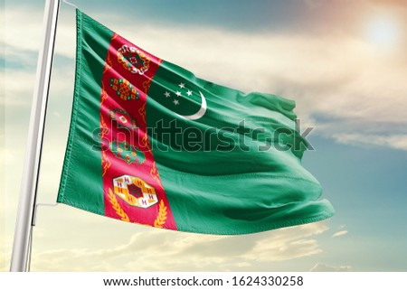 Waving Flag of Turkmenistan in Blue Sky. Turkmenistan Flag on pole for Independence day. The symbol of the state on wavy cotton fabric.
