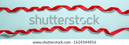 Banner of red velvet ribbon bows runs along the frame on blue background. Flat lay top view. Gift and holidays concept with copy space