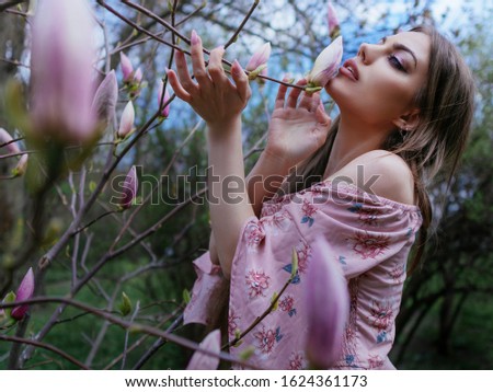 Portrait of beautiful young woman  on spring background with  magnolia trees.  Woman  wearied in dress.   