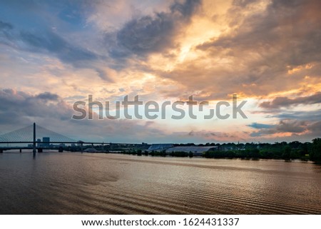 The sun shining behind the clouds over the river in the city