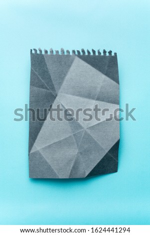 crumpled sheet of gray paper on a blue background. mocap grey paper