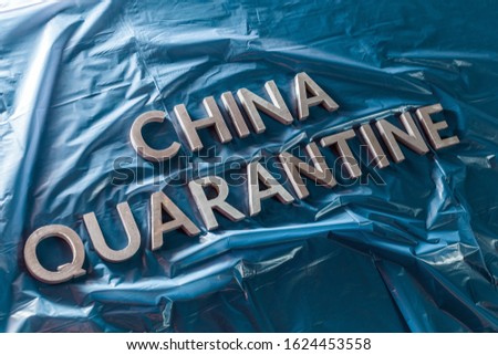 the words china quarantine laid with silver letters on crumpled blue plastic film in diagonal perspective