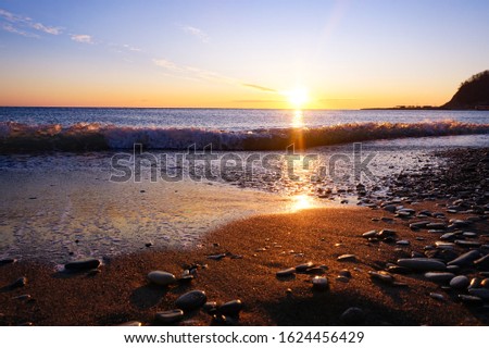 View from a sandy pebble beach to a beautiful sea sunset