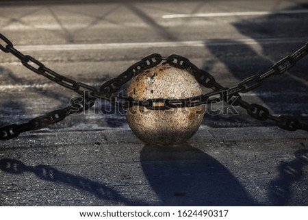 Granite ball and metal chain close-up on the pavement in summer