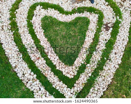 Top view  of heart shape white stones on the grass for landscape design. Backdrop for Valentine’s day or romantic background for wedding post card or marketing advertisment