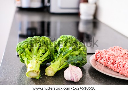 Fresh broccoli, garlic and ground beef on modern kitchen counter, ready to cook concept. 