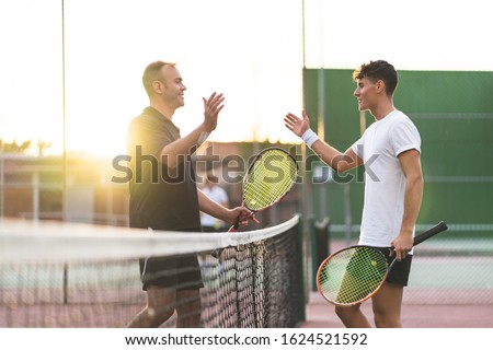 Father and Son Playing Tennis One to One. Family Doing Sport Together . Father Giving a Hug to His Son After Playing Tennis. Family Concept. Royalty-Free Stock Photo #1624521592