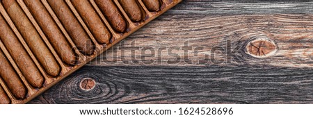 Cigars in wooden box. Cigar manufacturing in vintage traditional scale tools, top view. Handmade cigars in wood humidor. Collection hand rolled cigar pre labellin, banner Royalty-Free Stock Photo #1624528696