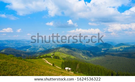 Idyllic beautiful landscape of nature in the mountains. Fragment of a blue sky with moving white clouds. Summer beautiful sunny day. Magic colorful background for screensavers.