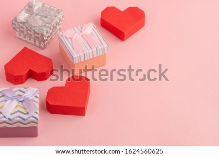 Red paper hearts and tiny gift boxes on pink background with copy space. Cute and lovely romantic template for your text.