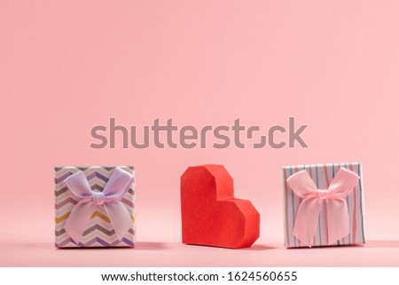 Two gift boxes and red paper heart on pink background. Handmade package for presents and Valentine's day card.