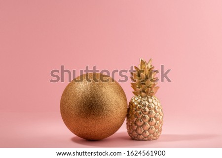 Golden glitter ball and painted pineapple on pink background. Minimalistic design for luxury party.