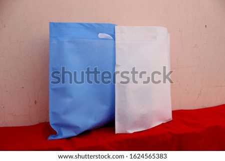 Royal Blue and white color NON WOVEN Polypropylene Shopping Bags on red Table.  Biodegradable Bags. Save Earth. World Environment Day Concept.