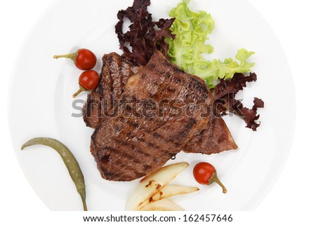 meat food : two grilled steak with chili and red peppers , green lettuce salad , on dish isolated over white background