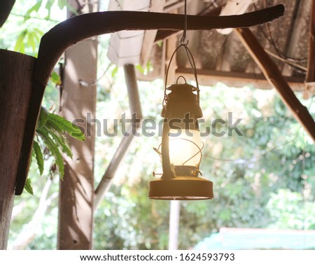 old hurricane lamp hanging on wooden post