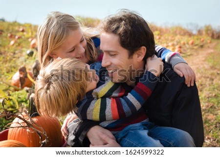 Father with son and daughter in pumpkin patch during fall autumn season